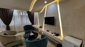 A modern living room with a sofa, a coffee table, and a TV mounted on the wall. - Ohu Palace Hotel (Fergana)