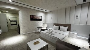 A modern hotel room with a large bed, a small table, a chair, and a desk. - Ohu Palace Hotel (Fergana)