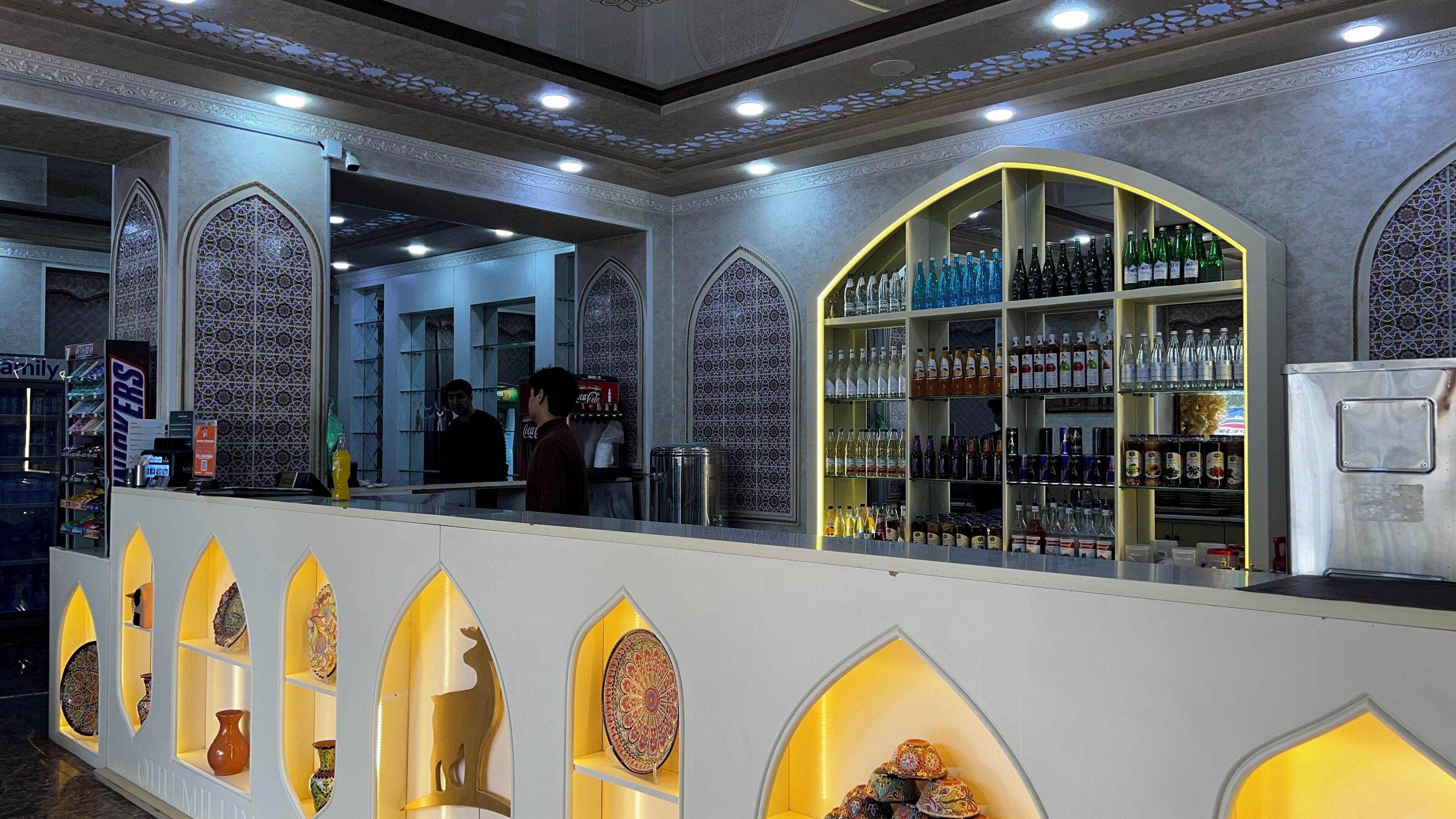 Una zona de bar con estantes llenos de bebidas en botella y objetos decorativos.