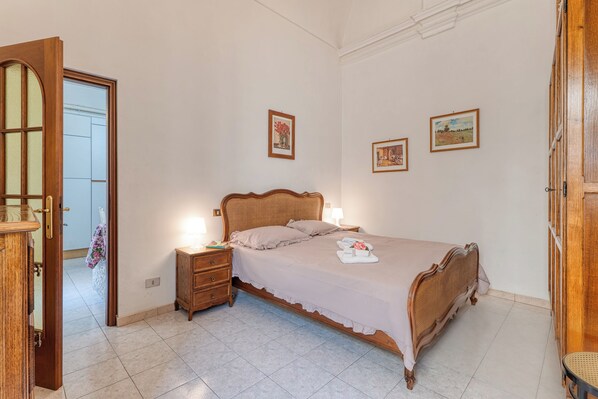 A bedroom with a wooden bed, bedside tables, and framed pictures on the wall. - Casa Lilly Sanremo La Pigna Old Town Hideaway (Sanremo)