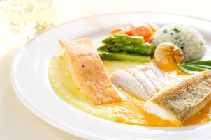 Une assiette de nourriture comprenant du poisson, des légumes et du riz.