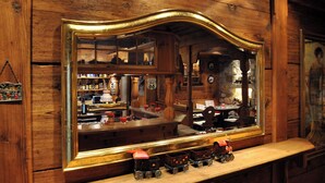 Espejo de marco de madera que refleja una zona de bar, incluyendo una estantería con botellas y un pequeño tren de juguete.