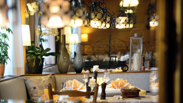 Una mesa de comedor decorada con velas, copas y un centro de mesa ornamental.