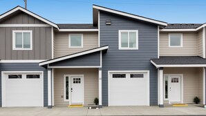 A row of three townhouses with two garages each, a front door, and a small porch area.