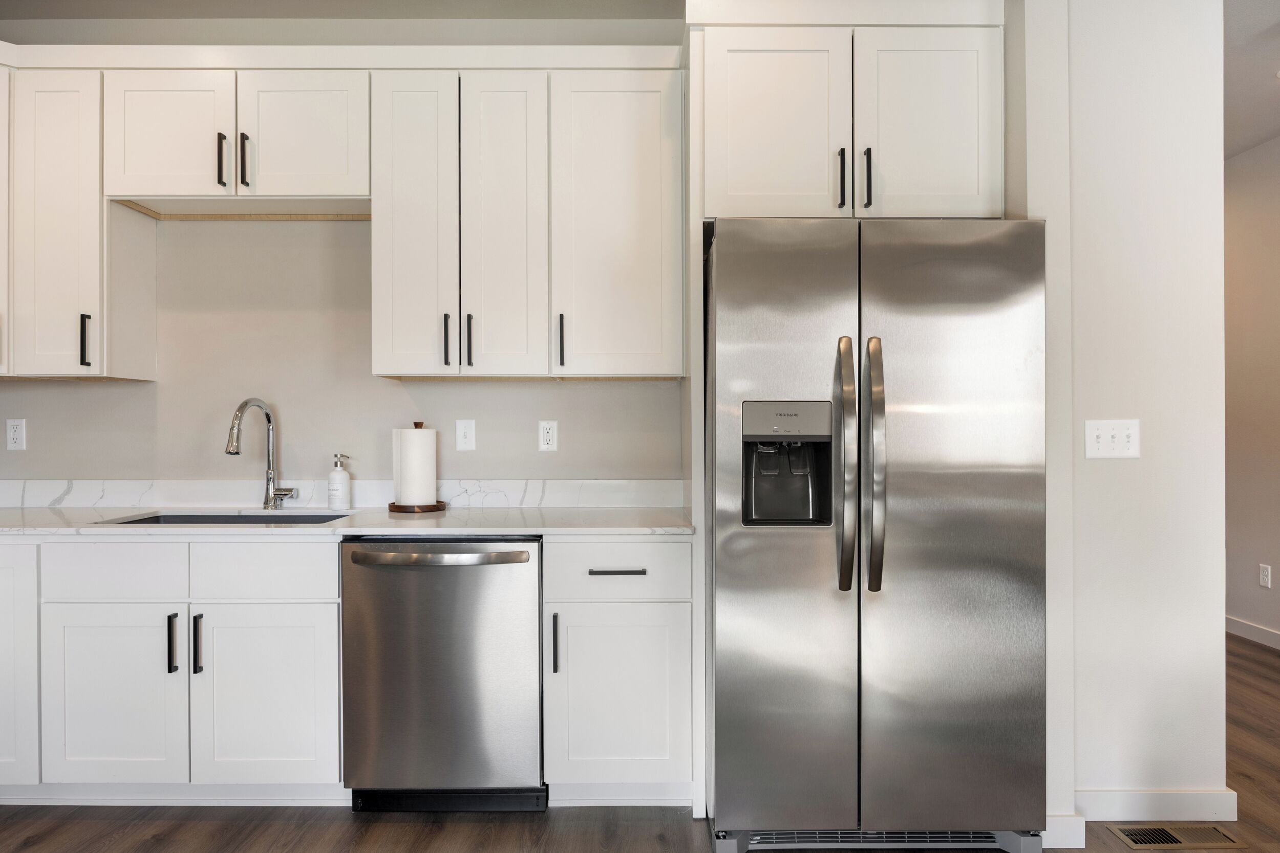 A modern kitchen with white cabinets, stainless steel appliances, and a dishwasher.