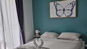 A hotel room with a bed, a teal wall, a butterfly artwork, and a swan towel art. - Skyline Serenity  1Bed T2-721 (Chalong)
