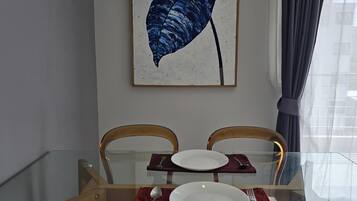Un comedor con una mesa de vidrio, dos sillas y un cuadro en la pared.