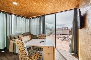 Una habitación moderna con techo de madera, un sofá, una mesa y vistas al exterior.