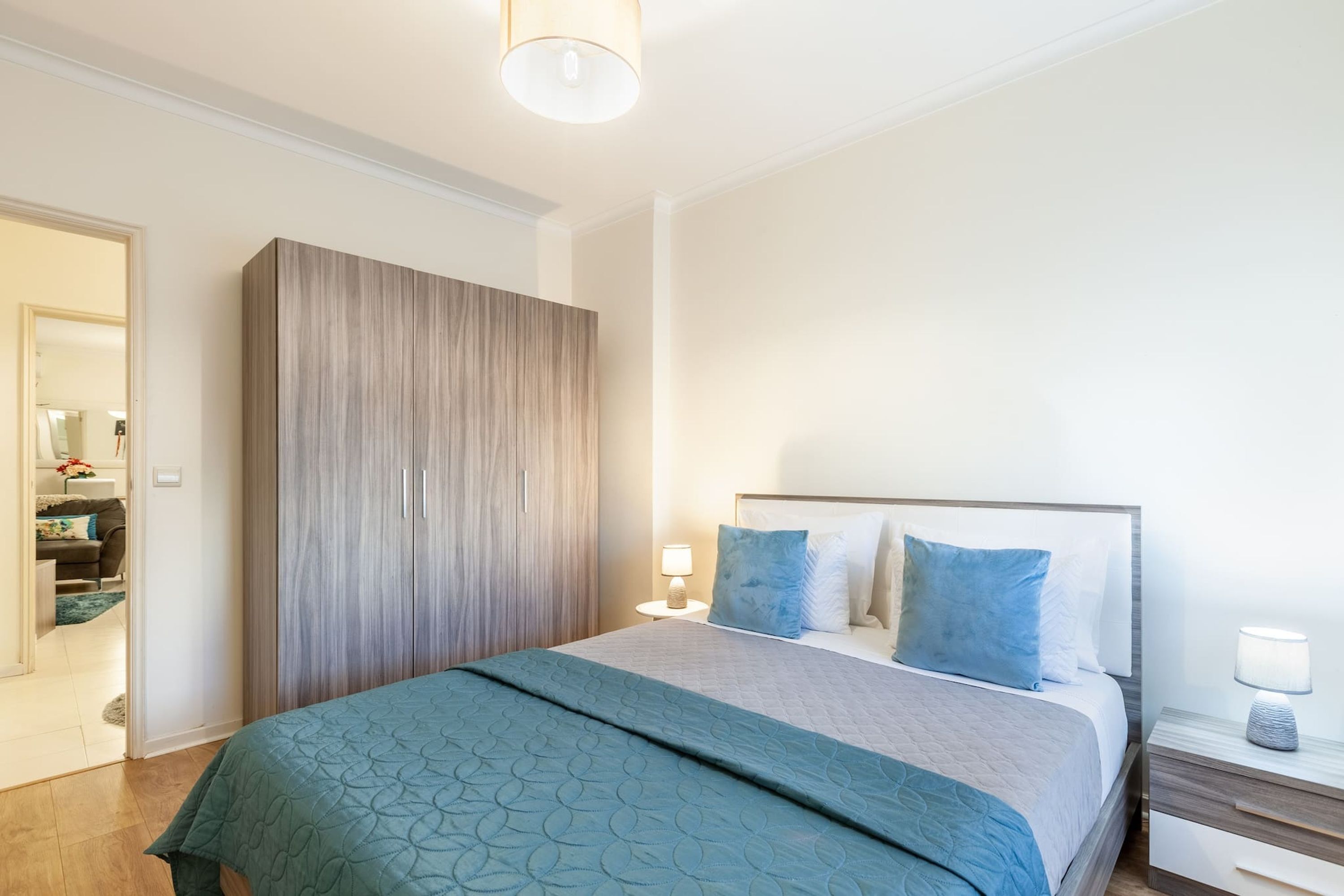 A bedroom with a bed, bedside tables, a wardrobe, and a mirror.