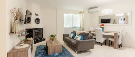 Uma sala de estar moderna com sofá, mesa de centro e um espaço de jantar com mesa e cadeiras.