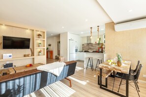 A modern kitchen with a dining area, wooden flooring, and a flat-screen TV. - Apartamento L rio - Minho s Guest (Braga)