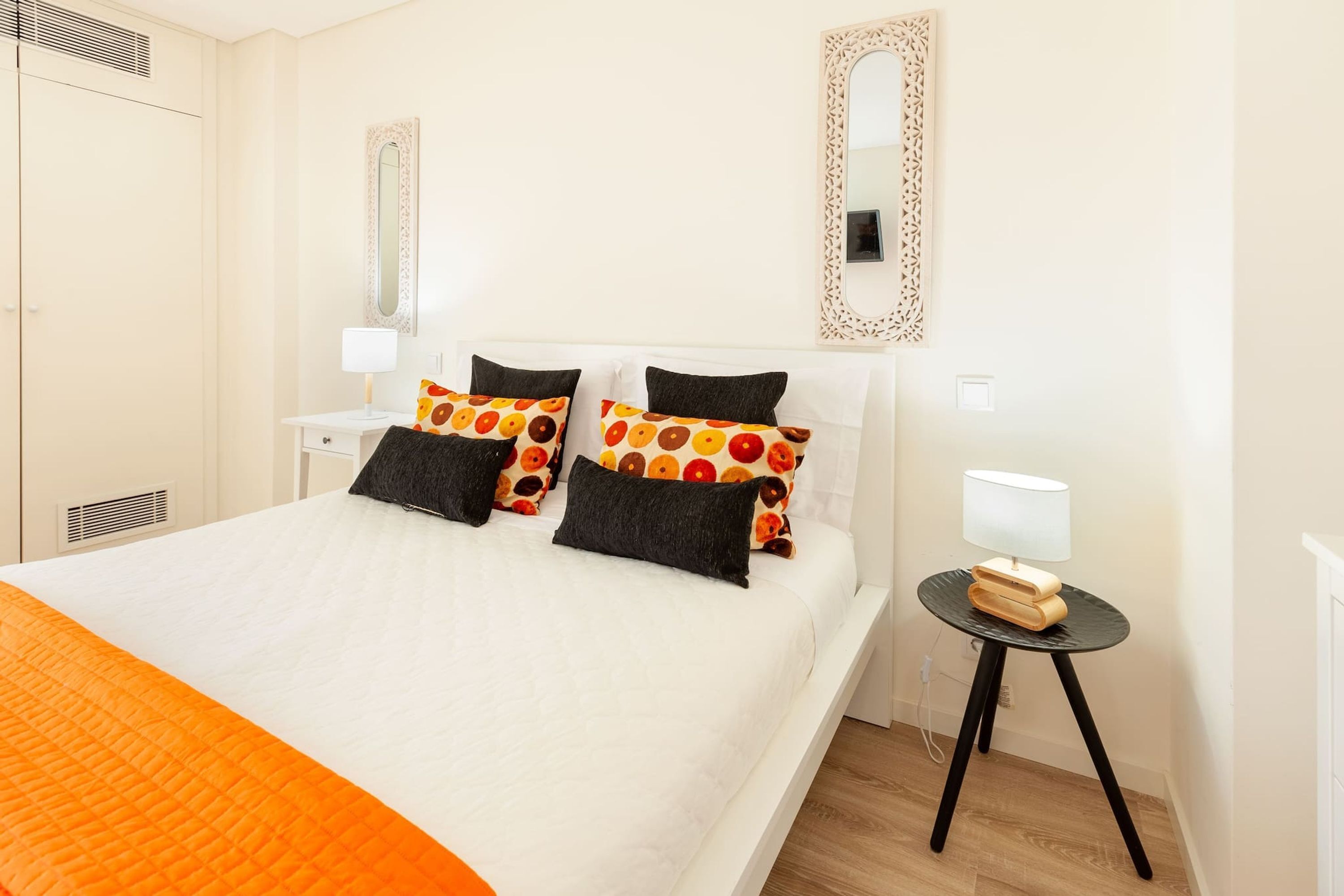 Ein Hotelzimmer mit einem Bett, zwei Nachttischen, einem Spiegel und einem Kleiderschrank.