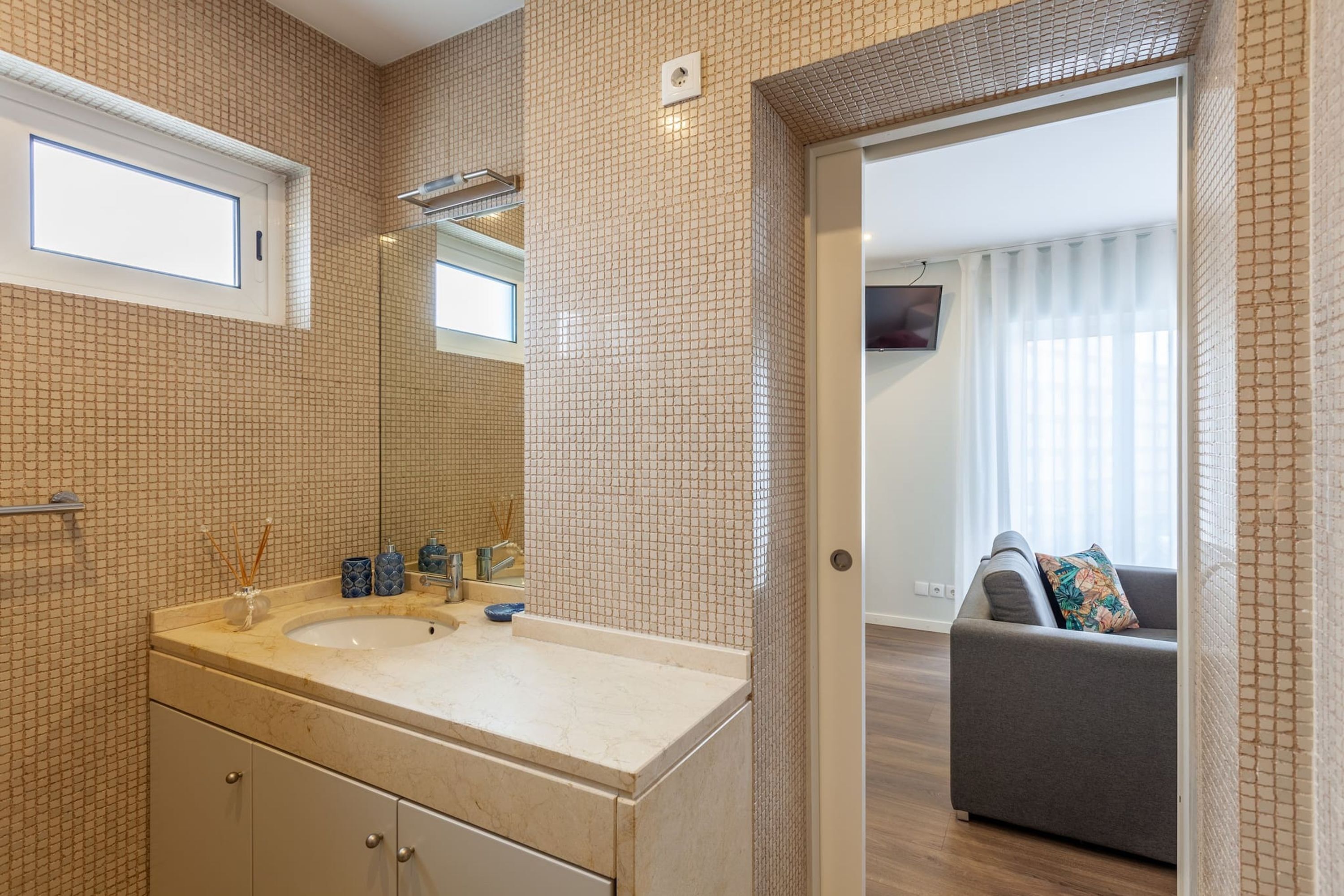 Ein Badezimmer mit großem Spiegel, doppeltem Waschbecken und Fenster.