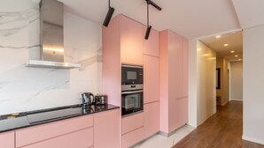 Een moderne keuken met roze kastjes, een rvs afzuigkap en een zwart aanrecht.