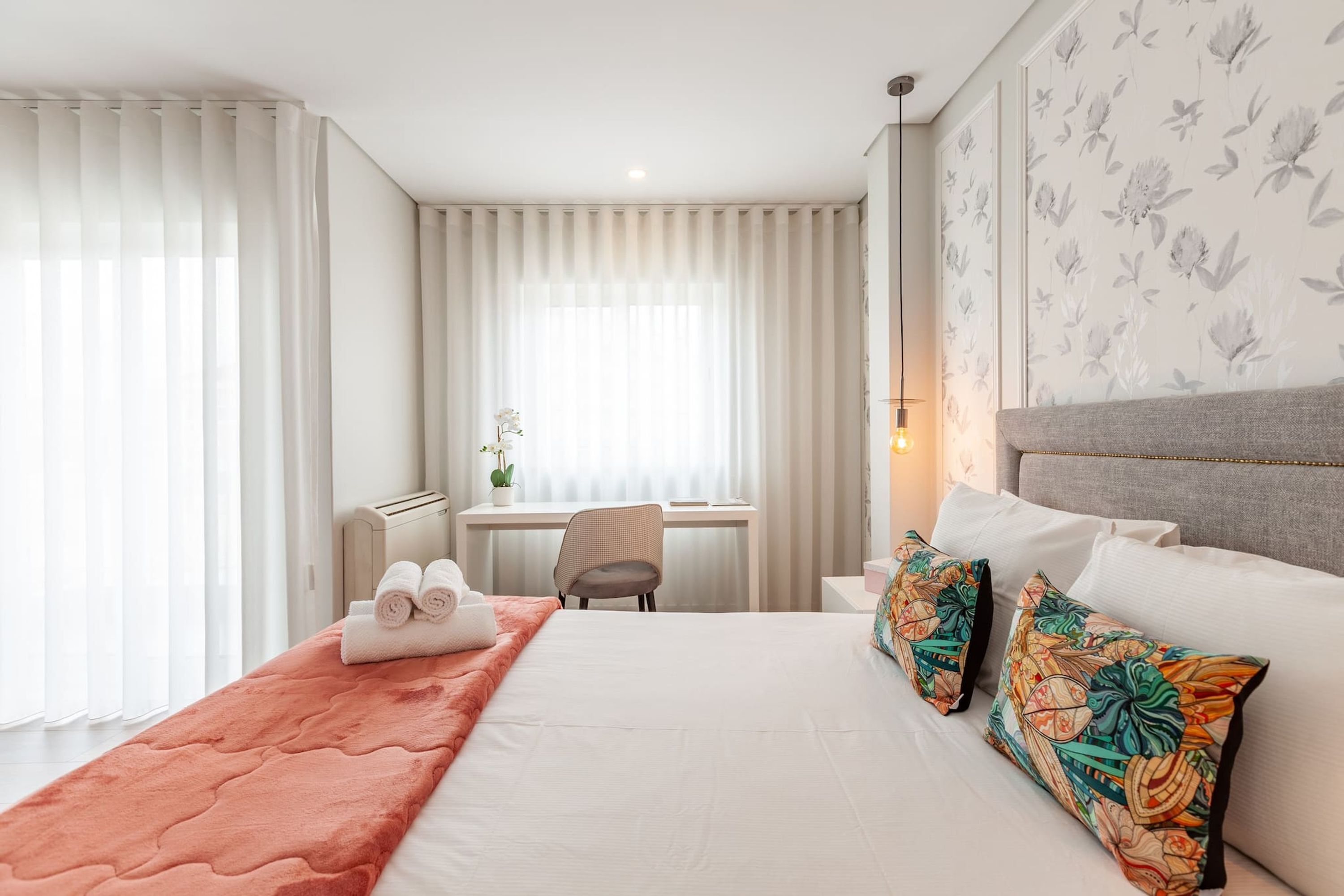 A hotel room with a bed, a desk, and a chair.