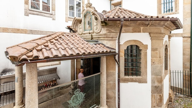 Un bâtiment traditionnel avec un toit en tuiles, des colonnes en pierre et une balustrade en verre.