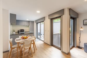 A modern kitchen with white cabinets, a microwave, and a dining area with a table set for two.