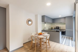 A modern kitchen with grey cabinets, a microwave, and a tiled backsplash.