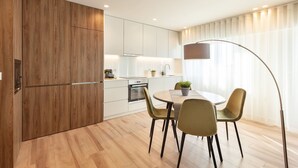 Eine moderne Küche mit Holzschnitzereien, einem Essbereich mit zwei Stühlen und einem großen Fenster mit Vorhängen.