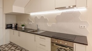 Eine moderne Küche mit schwarzem Arbeitsplatz, weißen Schränken, einer Mikrowelle, einem Spülbecken und einem Herd.