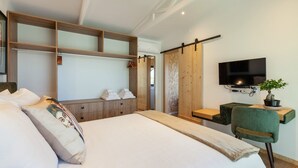 Una habitación de hotel moderna con una cama grande, un televisor montado en la pared, un escritorio de madera y una silla verde.