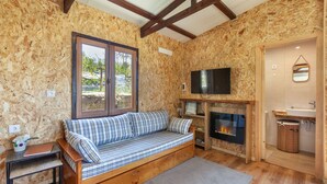 Una habitación acogedora con piso de madera, un sofá con cojines a rayas, un televisor en la pared y una chimenea.