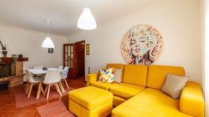 Un soggiorno luminoso con un divano giallo, un tavolo da pranzo con sedie e un camino.
