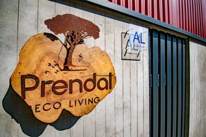 Ein Holzschild mit dem Aufdruck 'Prendal ECO LIVING' und einem Baumdesign.