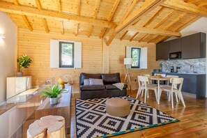 Ein modernes Interieur mit Holzbalkendecke, einer schwarzen Ledersofa, einem Essbereich und einer Küche mit Marmorarbeitsplatte.