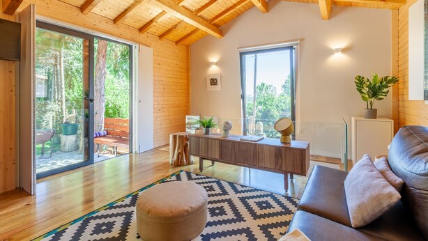 Un salon moderne avec des poutres en bois, un canapé, une table basse et une grande fenêtre.
