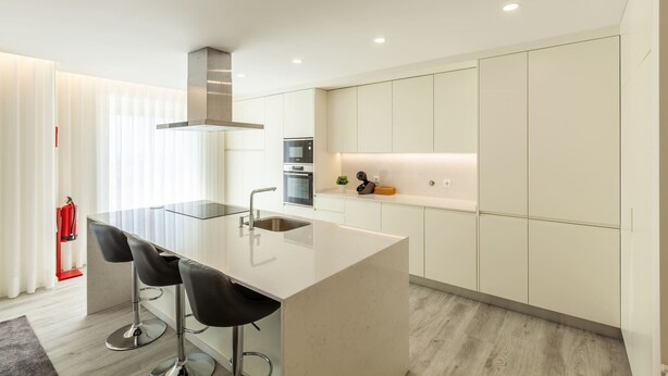 A modern kitchen with a central island, bar stools, stainless steel appliances, and a sleek design. - Apartamento Bela Vista - Minho s Guest (Esposende)