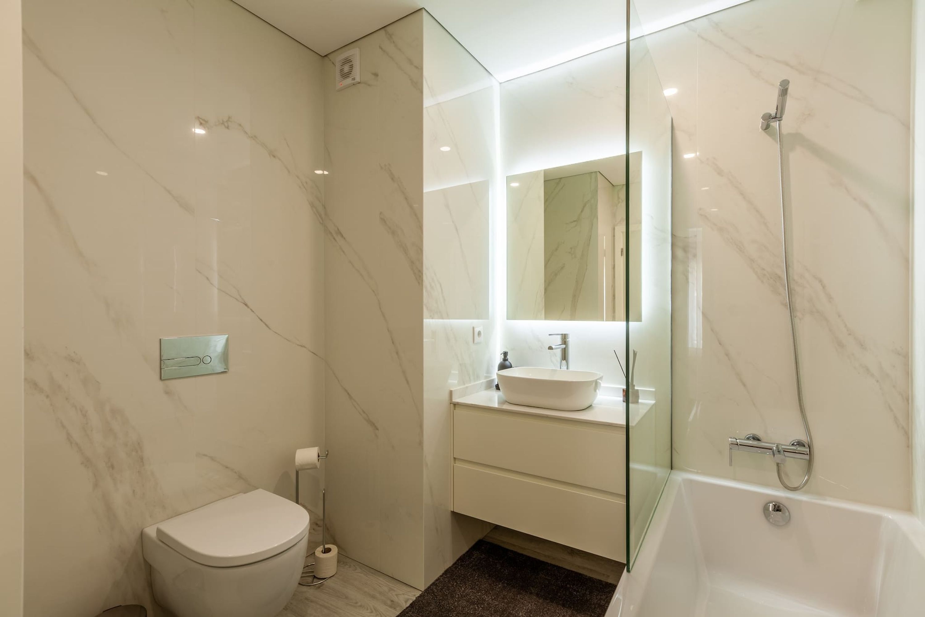 Un baño moderno con inodoro, lavamanos y ducha.