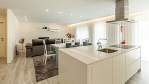 Una cocina moderna con una isla central, electrodomésticos integrados y un comedor con sofá y sillas.