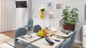 A modern dining area with a glass table, blue chairs, and a white cabinet. - Libert Lodge Apartment - Minho s Guest (Braga)