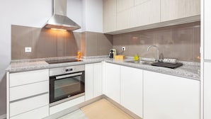 A modern kitchen with white cabinets, a stainless steel range hood, a built-in oven, a granite countertop, and a double sink. - Libert Lodge Apartment - Minho s Guest (Braga)
