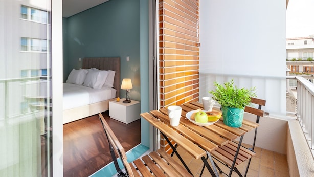 A balcony with a wooden table, a potted plant, and a breakfast setup. - Libert Lodge Apartment - Minho s Guest (Braga)