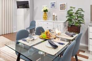 Un comedor moderno con una mesa de vidrio, sillas azules y un armario blanco.