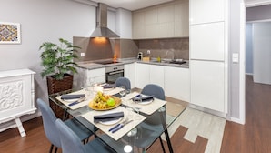 A modern kitchen with a dining area, featuring a glass table, chairs, and a potted plant. - Libert Lodge Apartment - Minho s Guest (Braga)