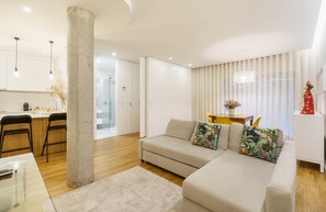 A modern living room with a sofa, a coffee table, and a dining area with chairs. - Casa do Alcaide - Minho s Guest (Braga)