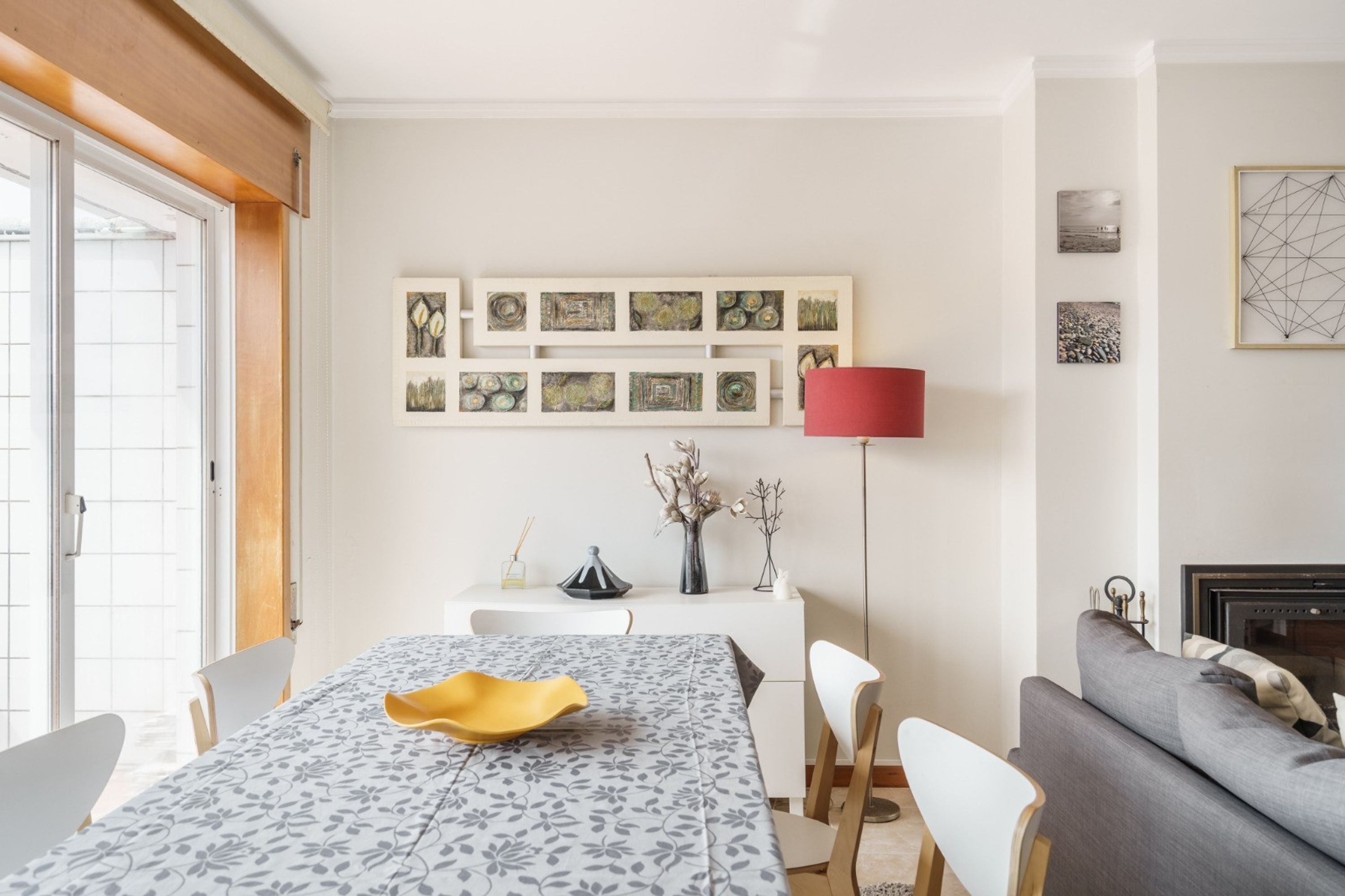 Una zona de comedor con una mesa lista para dos personas, un sofá y una chimenea.