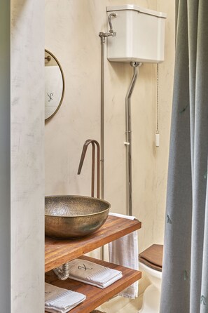 A bathroom with a wooden shelf holding a bowl, a towel rack, and a toilet with a chain. - Casa do Xico - Minho s Guest (Guimarães)