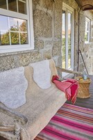 Un muro de piedra con un banco de madera, una cesta de mimbre con una taza y una alfombra colorida a rayas.