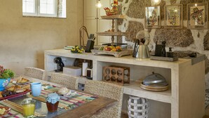 A rustic kitchen with a stone wall, wooden counter, and various kitchen items. - Casa do Xico - Minho s Guest (Guimarães)