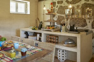 Una cocina rústica con pared de piedra, encimera de madera y varios utensilios de cocina.