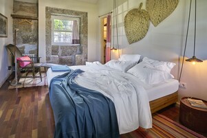 Un dormitorio con cama, suelo de madera, pared de piedra y una lámpara colgante.