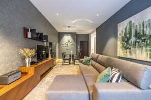 A modern living room with a sofa, TV, wooden console, and a dining area with chairs and a table. - Ch os Design By Minho s Guest (Braga)