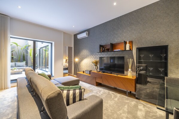 A modern living room with a large flat-screen TV, a wooden entertainment unit, and a glass cabinet with decorative items. - Ch os Design By Minho s Guest (Braga)