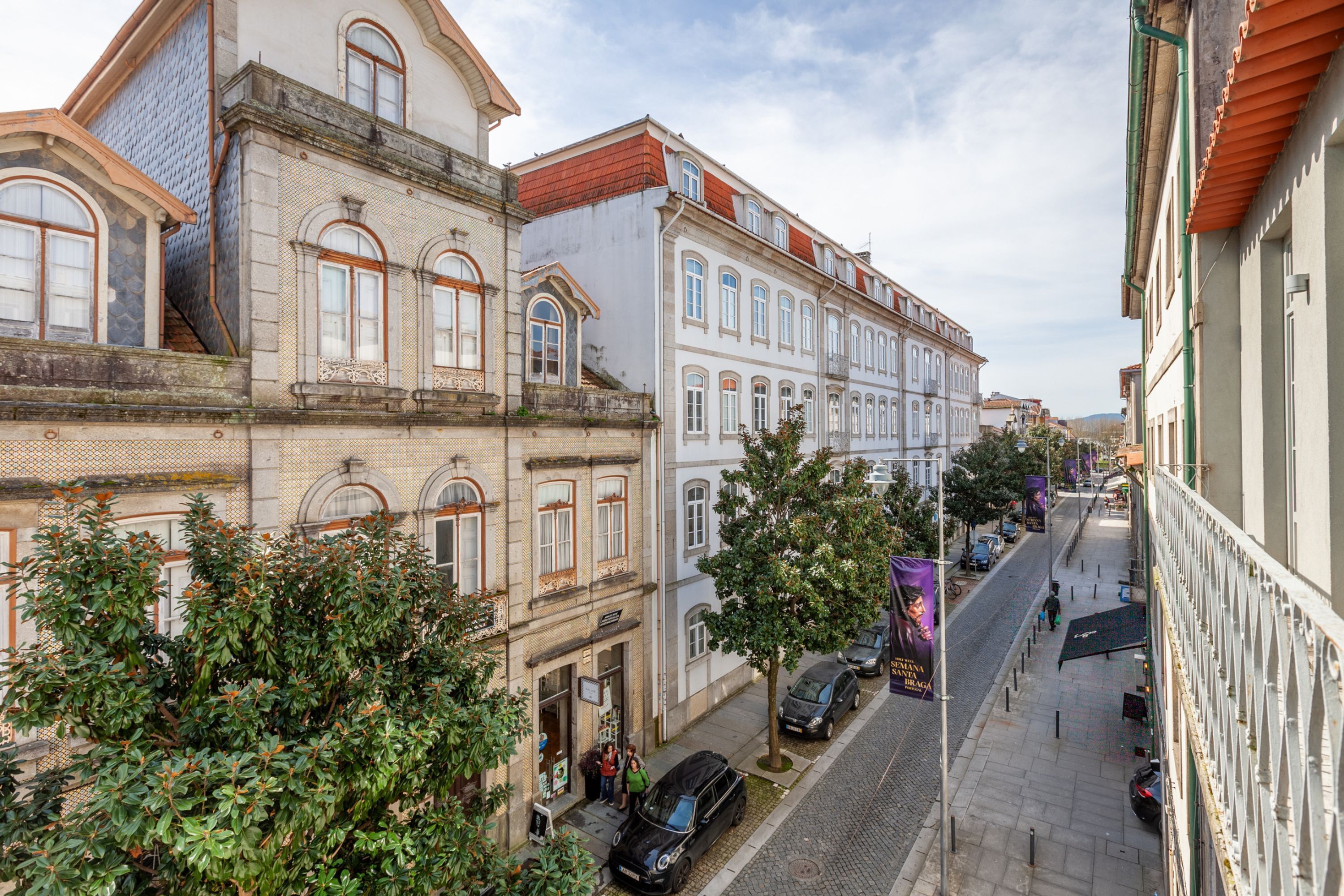 Vista de una calle con edificios históricos, adoquinado y coches estacionados.