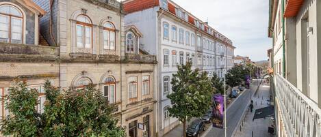 Vista de una calle con edificios históricos, adoquinado y coches estacionados.