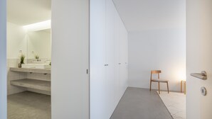 Un bagno moderno con un grande specchio, un lavandino e una sedia.
